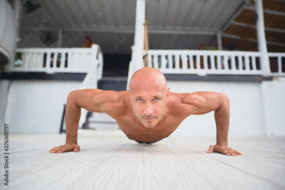 Obraz premium Young and handsome man is doing some push-ups. He is using loops for that 