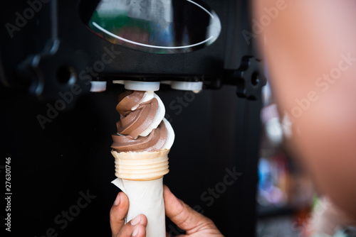 Human hand holding cone with twisted ice cream from machine photo