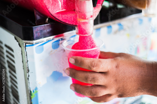 фотографія Human hand serving slushy drink from slushy  machine