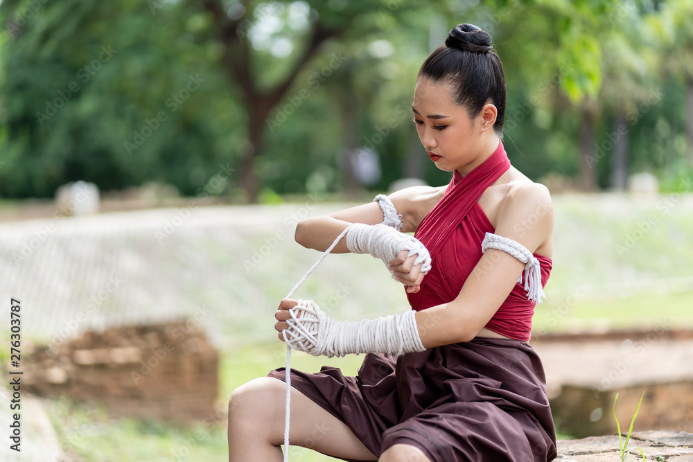 Close-up of a young woman Muay Thai fighter preparing and wrapping her hand with traditional hemp ropes before the fight or training. Close-up of a young woman Muay Thai fighter preparing and wrapping her hand with traditional hemp ropes before the fight or training.