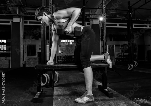 Junge fitte Frau mit Muskeln beim Fitness. Die hübsche athletische Sportlerin macht Krafttraining mit Gewichten. Workout mit einer Hantel. Schwarz und weiß. © Julia43