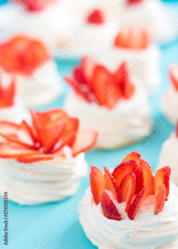 Beautiful pavlova cakes with strawberries on a blue background. Selective focus. Tasty sweet breackfast. Wedding morning. Meringue with cream.