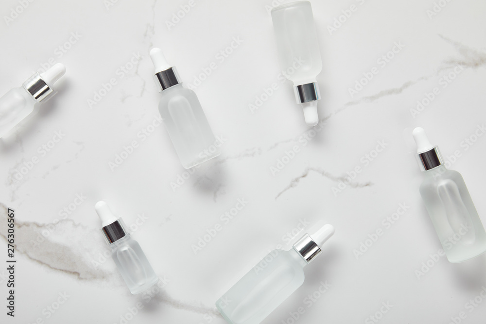 top view of cosmetic glass bottles on white surface top view of cosmetic glass bottles on white surface