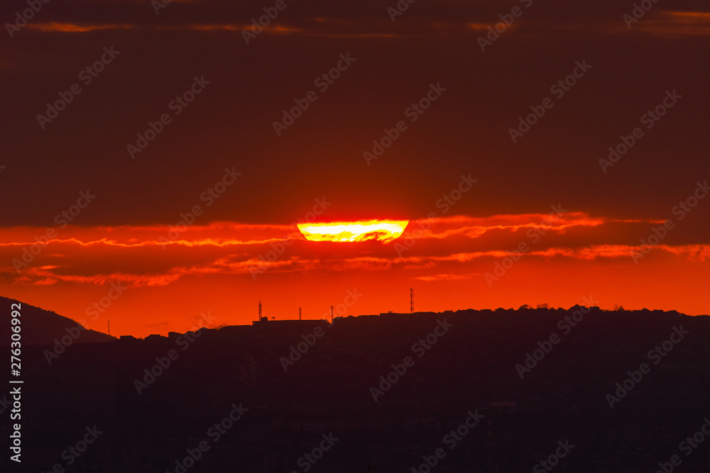 Red sun at sunset under the clouds above the horizon. Epic dramatic picture of the sky Red sun at sunset under the clouds above the horizon. Epic dramatic picture of the sky
