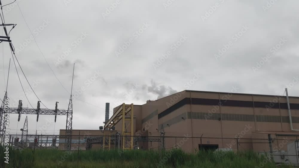 Steam rising from a steel plant, gray skies, brick building, railroad tracks Steam rising from a steel plant, gray skies, brick building, railroad tracks