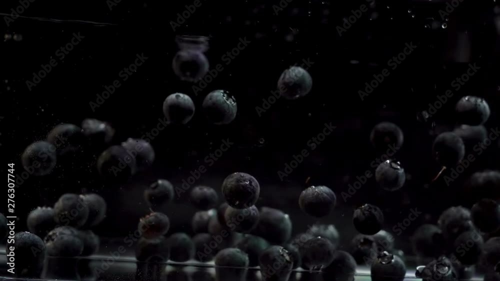 Blueberries Floating In Water Against Black Background in Slow Motion
