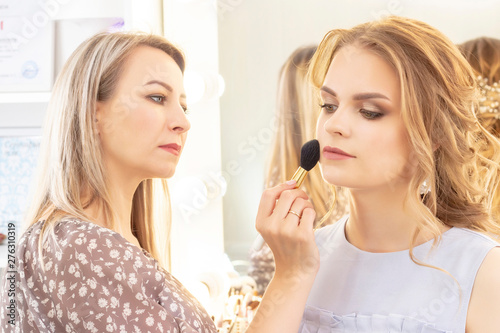 Makeup artist applies model makeup on face. bridal makeup, light evening make-up, in nude tones