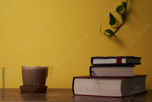  Coffee and books on a brown wooden table.
