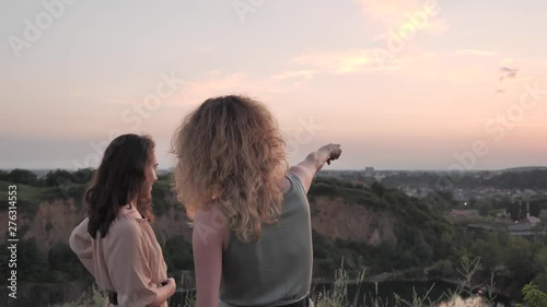Girls take a selfie against the sunset from the hill overlooking the city. View from the hill to the city. Two girls sharing a photo together. photo