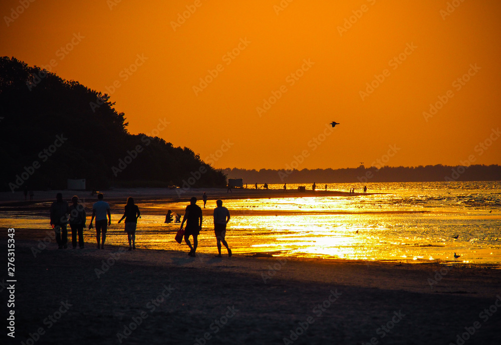 People on the beach in the beautiful sunset on a hot summer day