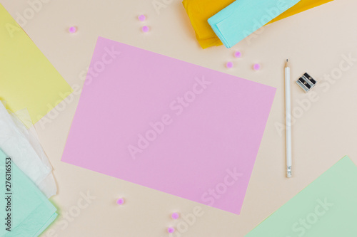 An overhead view of pink blank paper with pencil and sharpener on colored backdrop