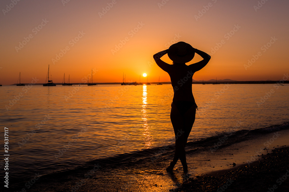 Sunset, sexy woman silhouette. Carefree woman enjoying the sunset on the beach. Happy lifestyle. Mallorca. Es Prenc beach.