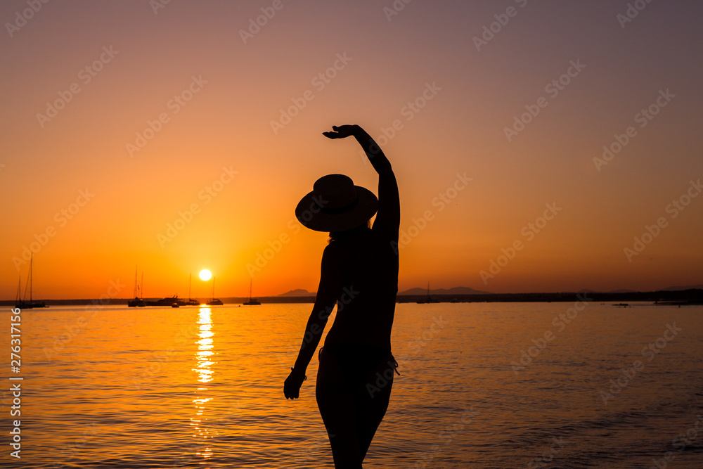 Sunset, sexy woman silhouette. Carefree woman enjoying the sunset on the beach. Happy lifestyle. Mallorca. Es Prenc beach.