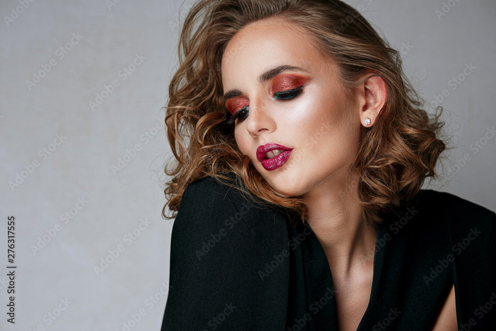 Fototapeta premium Fashion portrait of seductive brunette girl with bright makeup and wavy hair. Space for text