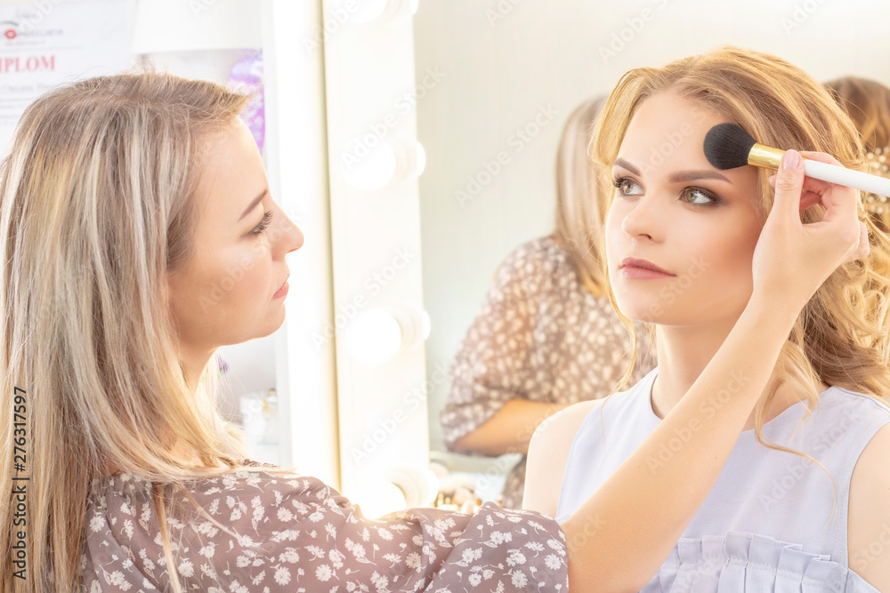 Makeup artist applies model makeup on face. bridal makeup, light evening make-up, in nude tones Makeup artist applies model makeup on face. bridal makeup, light evening make-up, in nude tones