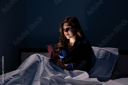 Beautiful woman working on the phone sitting in the bed