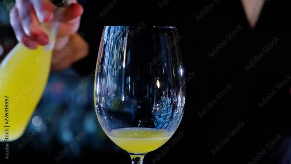 Bartender preparing alcohol cocktail mimosa with orange juice and cold dry champagne, gray bar counter background. Classic bellini cocktail in the bar, slow motion 4k