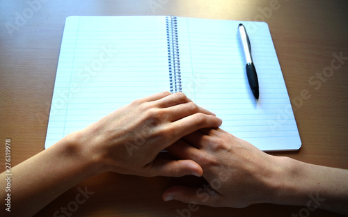 Folded Hands and a White Lined Notebook on a Desk 1