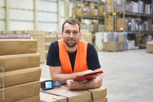 portrait of a friendly smiling storeman in a depot for logistic and shipping goods