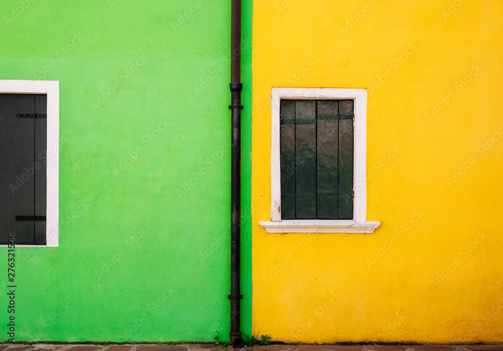 View of green and yellow stone house and small white windows with wooden shutters. Minimalism and free space for background concept.