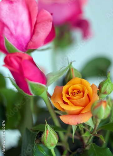 Colorful rose flowers bouquet in the vase with orange rose and buds in the foreground