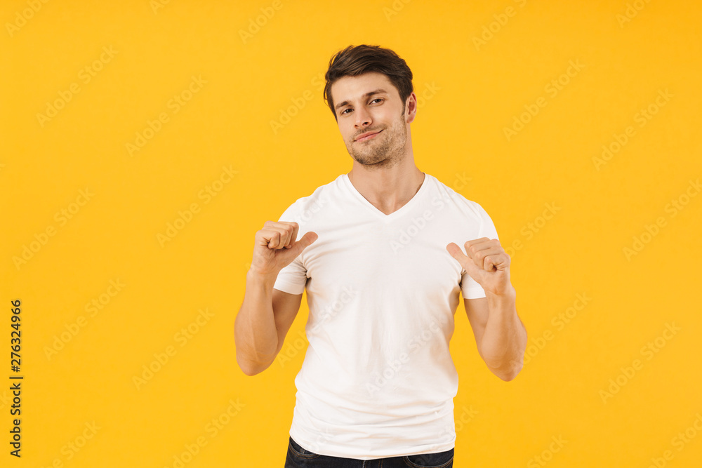 Photo of attractive man in basic t-shirt looking at camera and gesturing fingers at himself Photo of attractive man in basic t-shirt looking at camera and gesturing fingers at himself