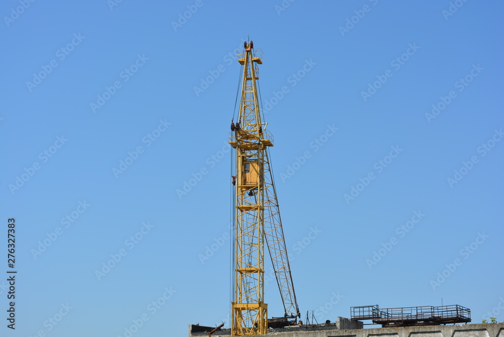 Large high-rise metal yellow crane on a background of blue sky. Large high-rise metal yellow crane on a background of blue sky.