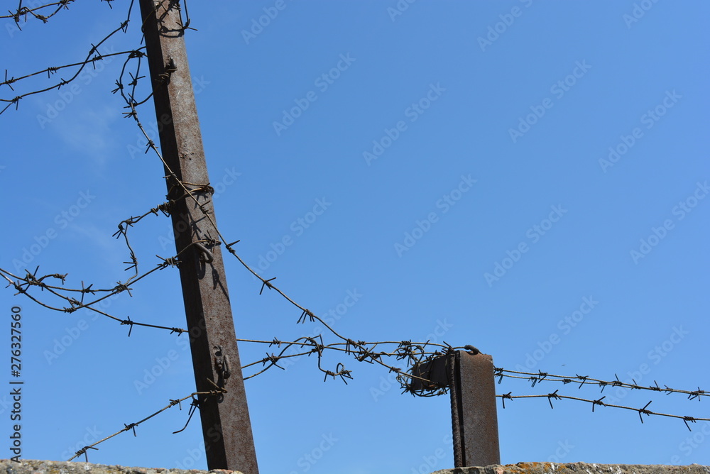Black metal fencing with barbed wires against thieves in the blue sky. Black metal fencing with barbed wires against thieves in the blue sky.