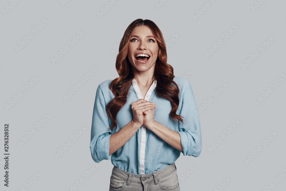 So happy! Attractive young woman smiling while standing against grey background So happy! Attractive young woman smiling while standing against grey background