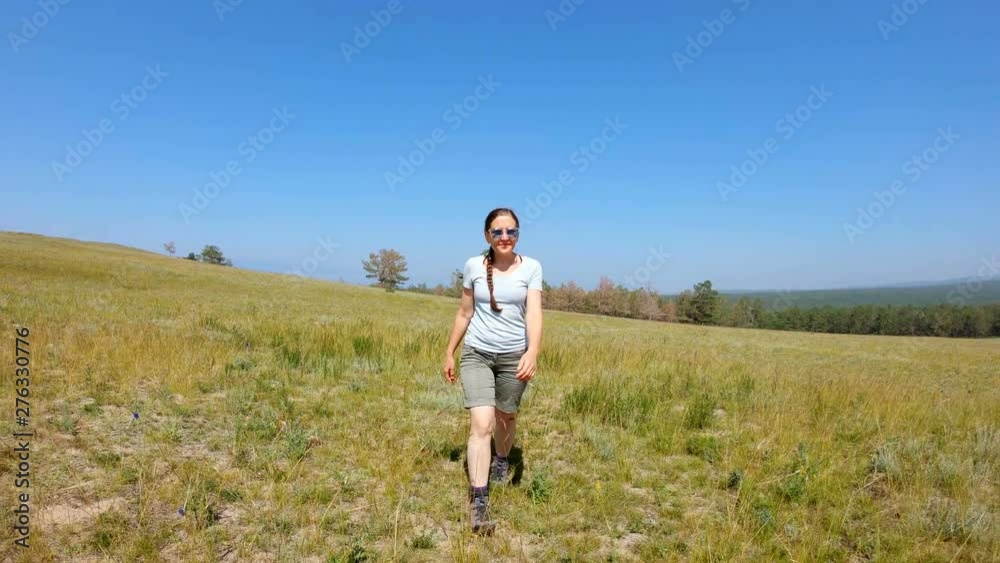 Girl with pigtail in blue glasses, in shorts walking in the field. Front view. Slow motion Girl with pigtail in blue glasses, in shorts walking in the field. Front view. Slow motion