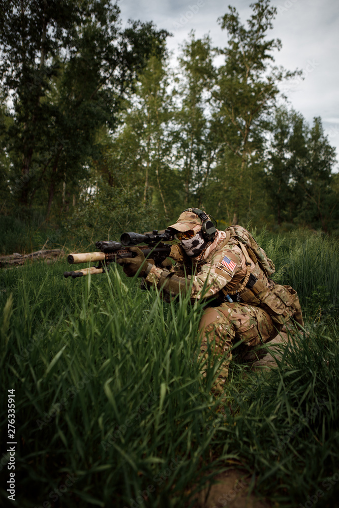 Portrait airsoft soldier with a rifle playing strikeball in outdoor in grass