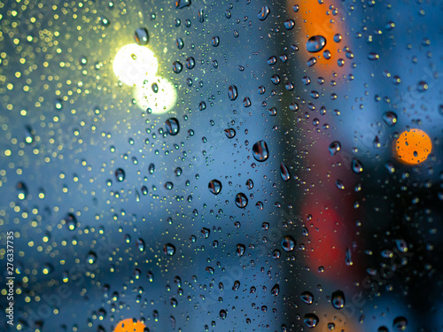 Rain drops texture on car window with colorful bokeh abstract background.