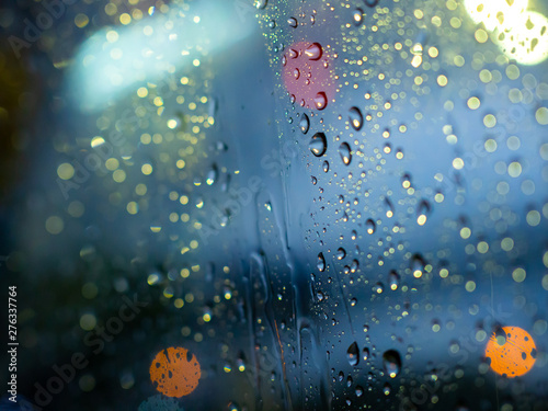 Rain drops texture on car window with colorful bokeh abstract background.