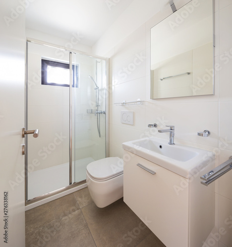 Modern minimalist white bathroom with shower and small window