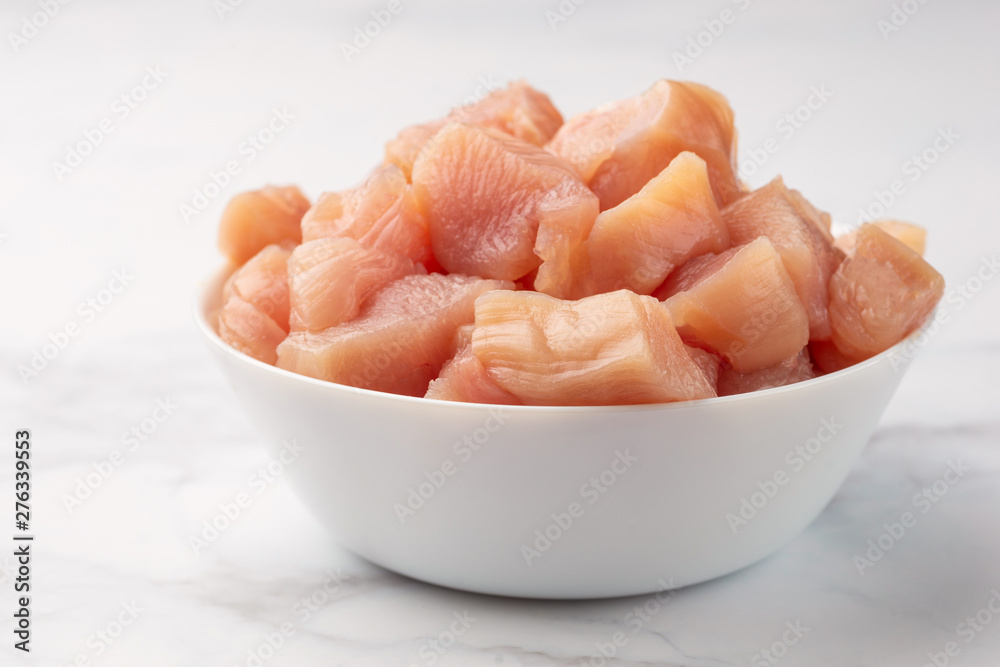 Raw chicken small pieces close up on marble background Raw chicken small pieces close up on marble background