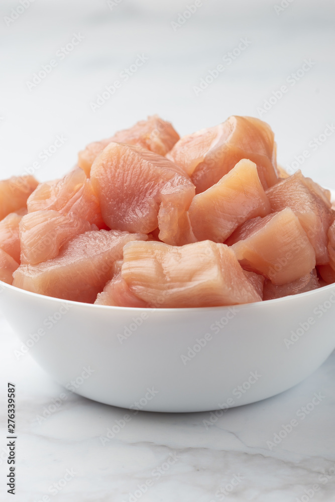 Raw chicken small pieces close up on marble background Raw chicken small pieces close up on marble background