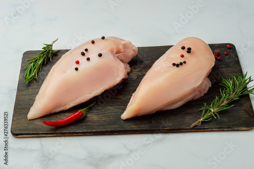 Raw chicken fillets on dark wooden board