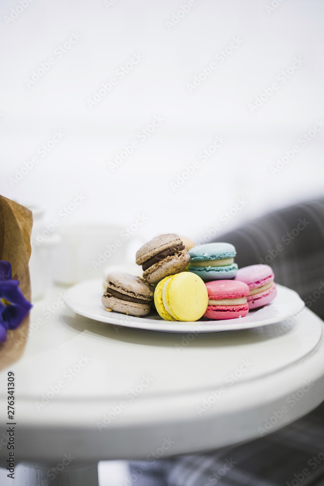 Many colorful macaroons on white ceramics plate over the table Many colorful macaroons on white ceramics plate over the table
