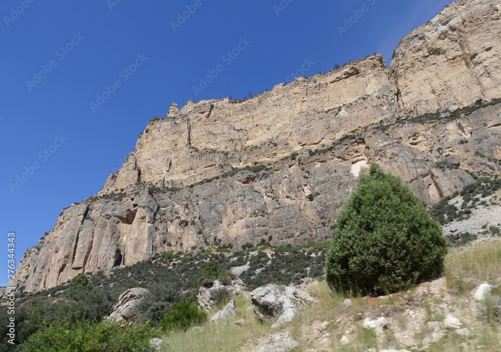 Side view of imposing rocky wall cliffs along the road through Bighorn Mountains in Wyoming, with beautiful clouds in the skies.
