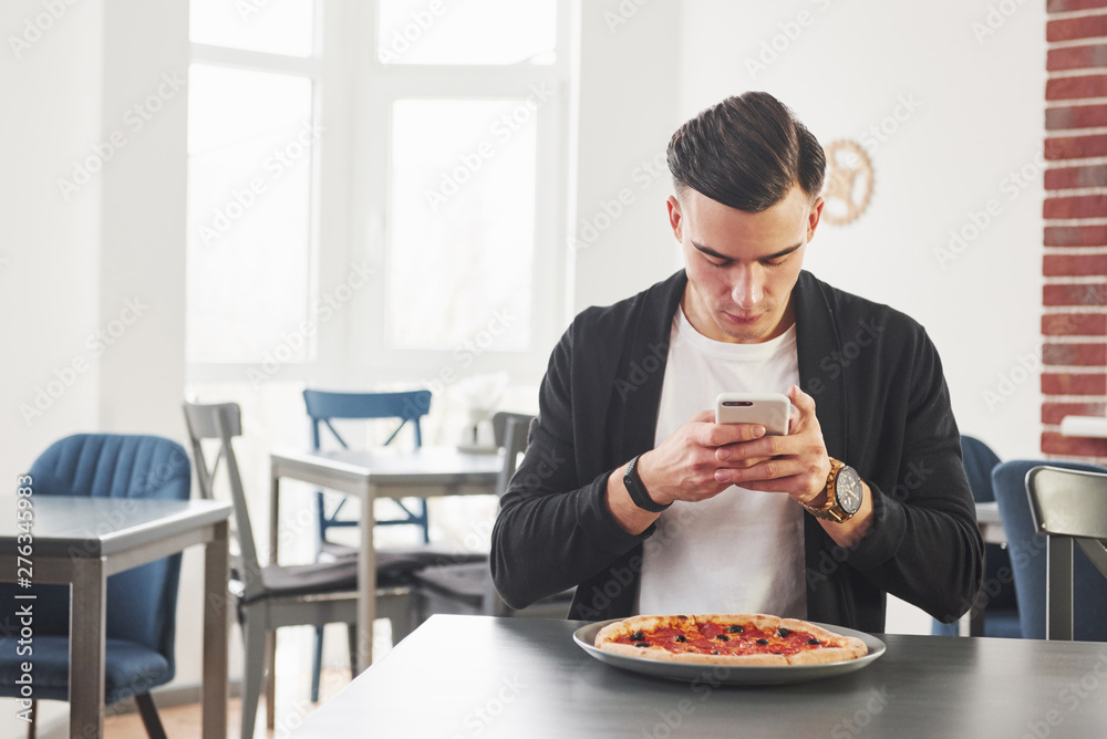 Having a breakfest with pizza at daytime. Young stylish man in black jacket Having a breakfest with pizza at daytime. Young stylish man in black jacket