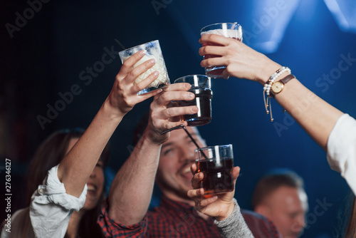Let's drink for our happiness. Group of young friends smiling and making a toast in the nightclub