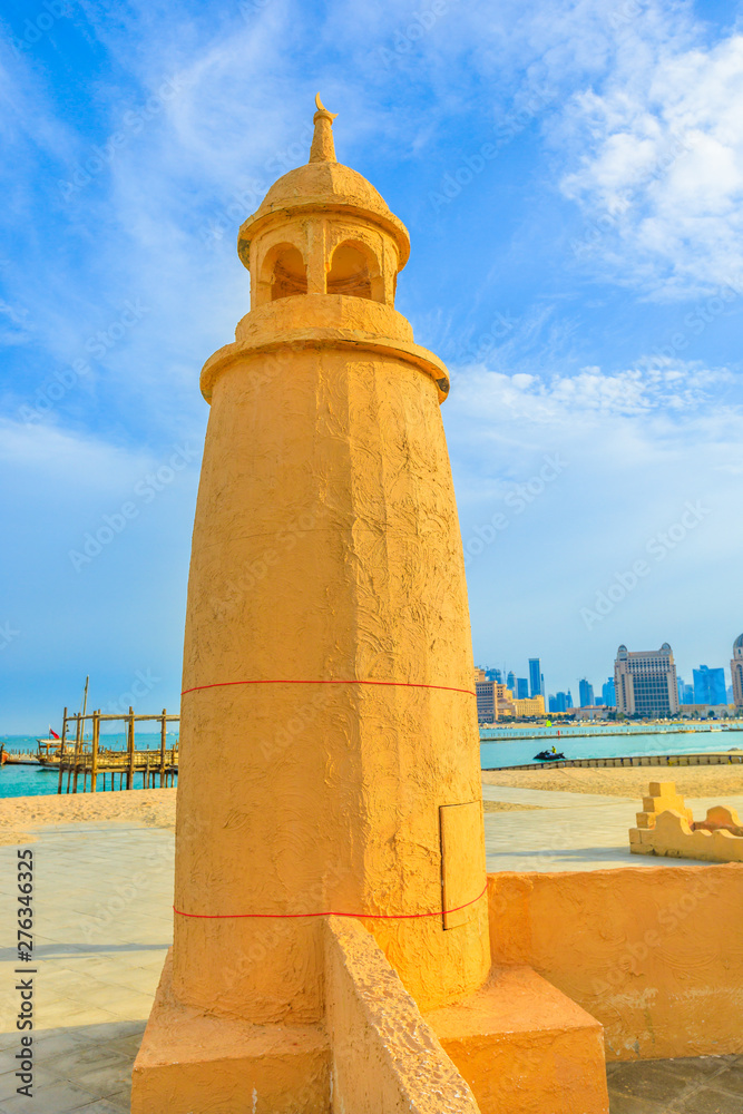 Katara Beach lighthouse with wooden boats and West Bay skyline on background in Doha Bay area near Katara cultural village. Qatar, Middle East, Arabian Peninsula. Vertical shot. Katara Beach lighthouse with wooden boats and West Bay skyline on background in Doha Bay area near Katara cultural village. Qatar, Middle East, Arabian Peninsula. Vertical shot.