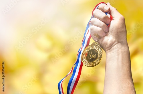 Gold medal with ribbon in hand on background