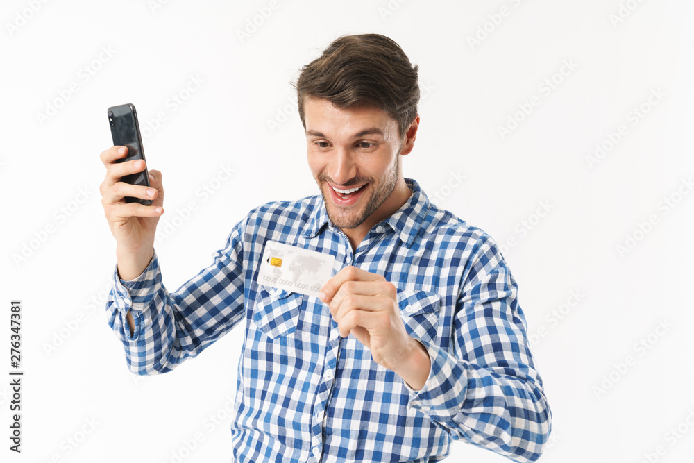 Photo of happy man in casual shirt holding credit card and smartphone Photo of happy man in casual shirt holding credit card and smartphone