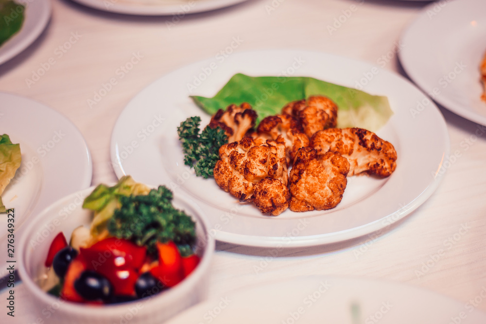 roasted cauliflower in breadcrumbs and vegetable salad on the table roasted cauliflower in breadcrumbs and vegetable salad on the table
