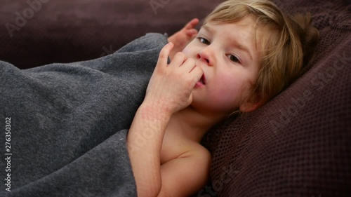 The girl pokes her finger in her nose. Pensive child photo