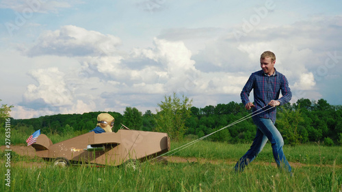 A little boy rides a homemade cardboard plane. Concept of friendly family