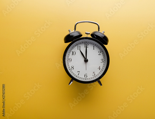 Alarm clock on yellow background top view. Concept of time
