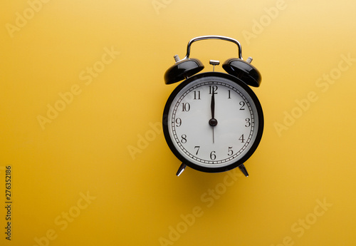Alarm clock on yellow background top view. Concept of time