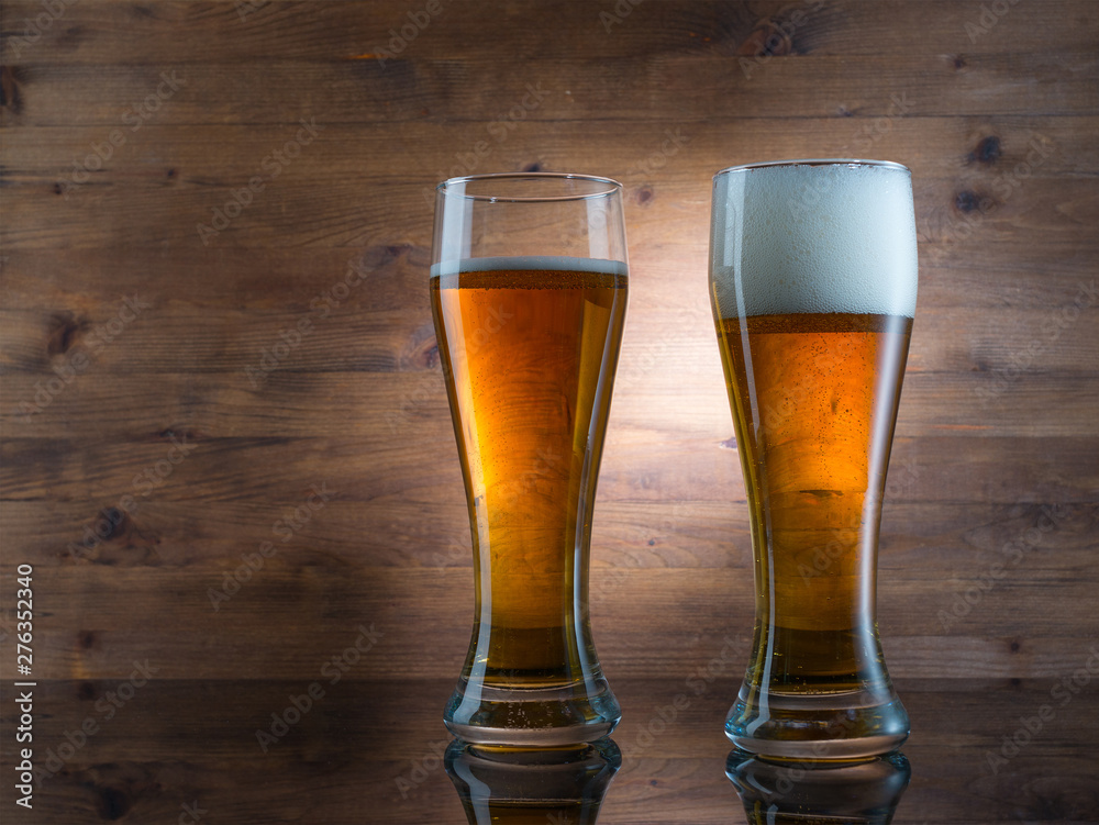 Two glasses of golden beer on wooden background